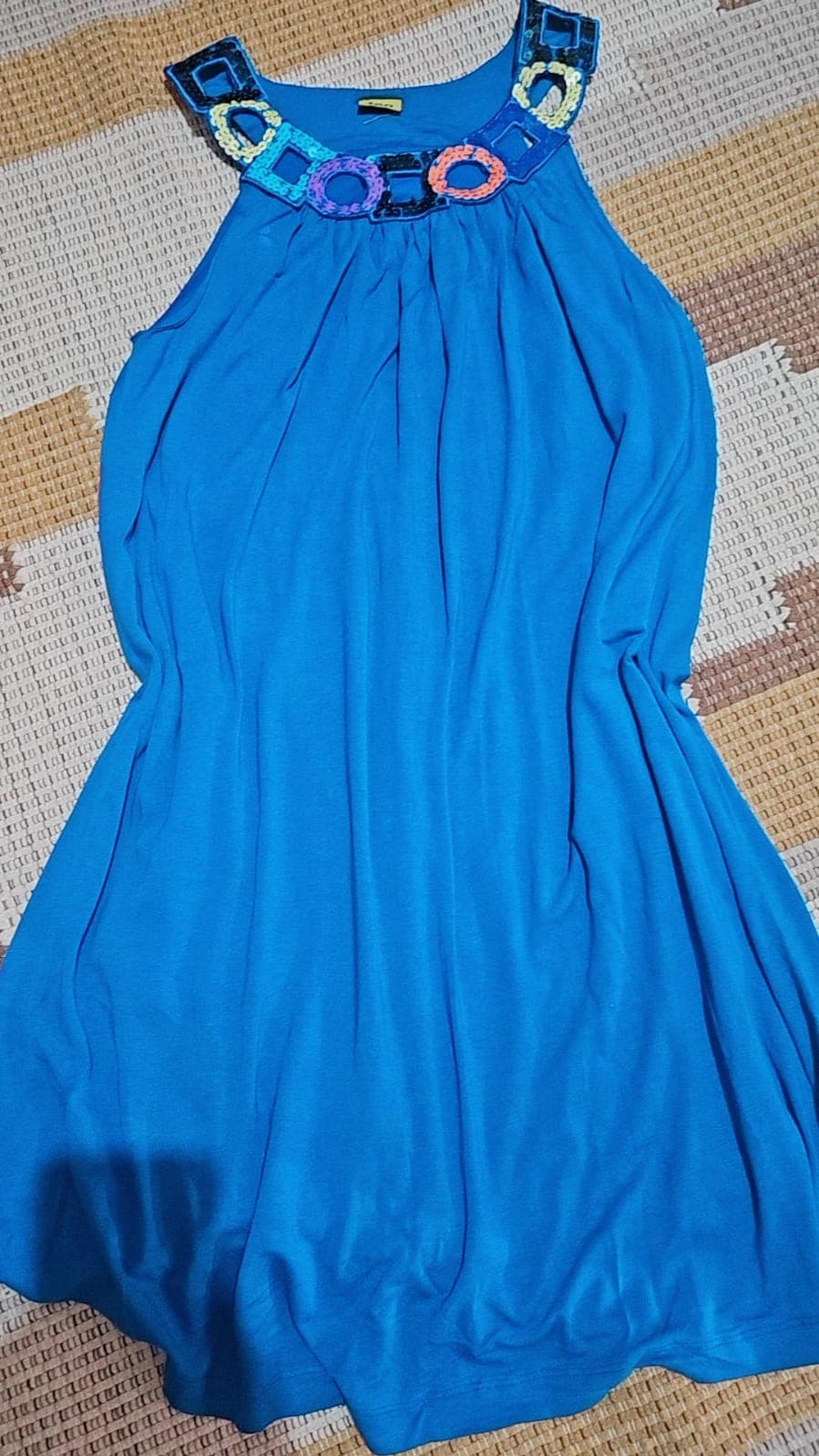 Vestido azul de malha sem manga, com a gola bordada em argolas de crochê e paetês em rosa, amarelo, laranja e azul