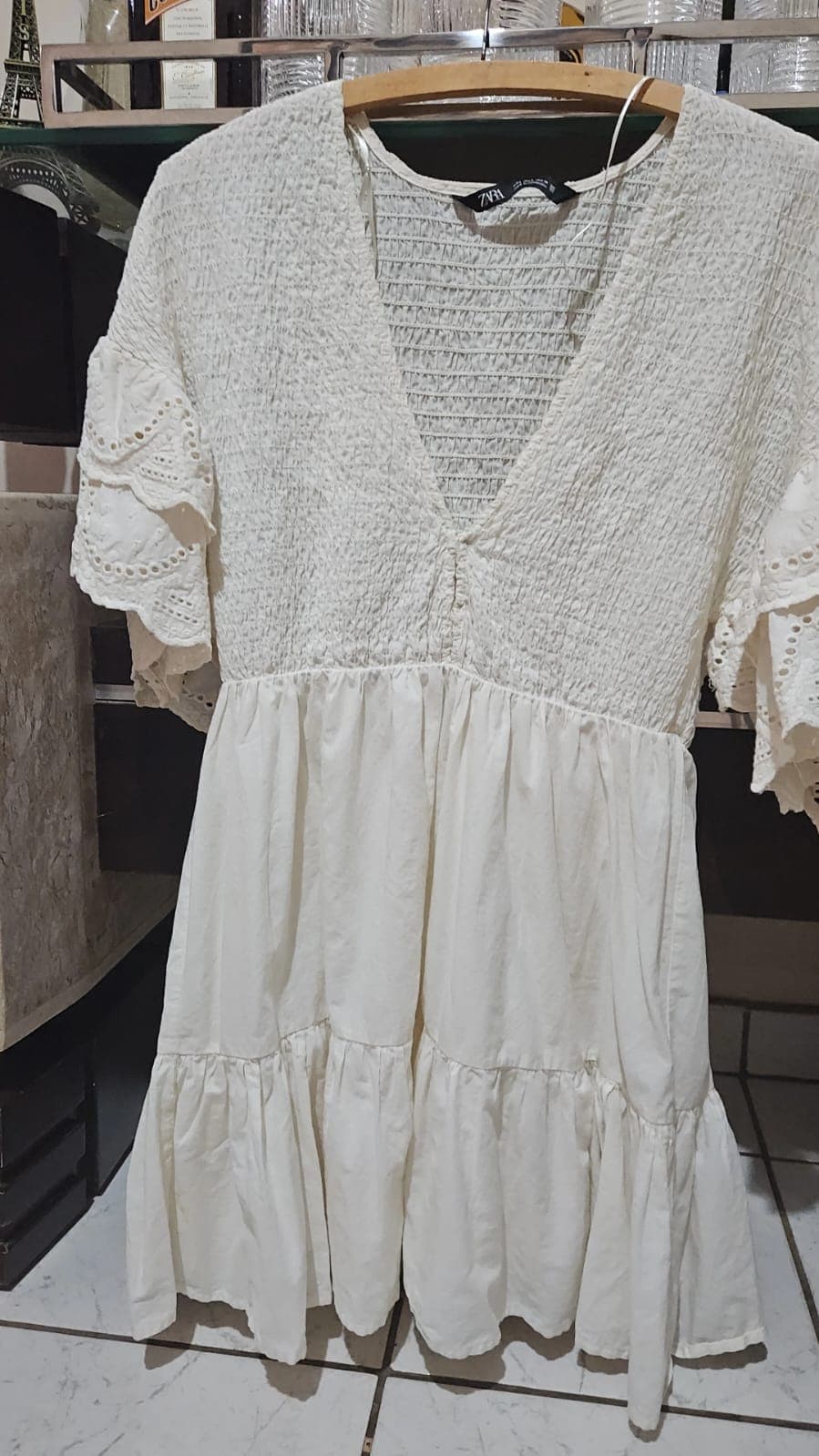 Vestido curto branco off-white no cabide, corpo todo franzido, decote V e mangas amplas em laise bordada